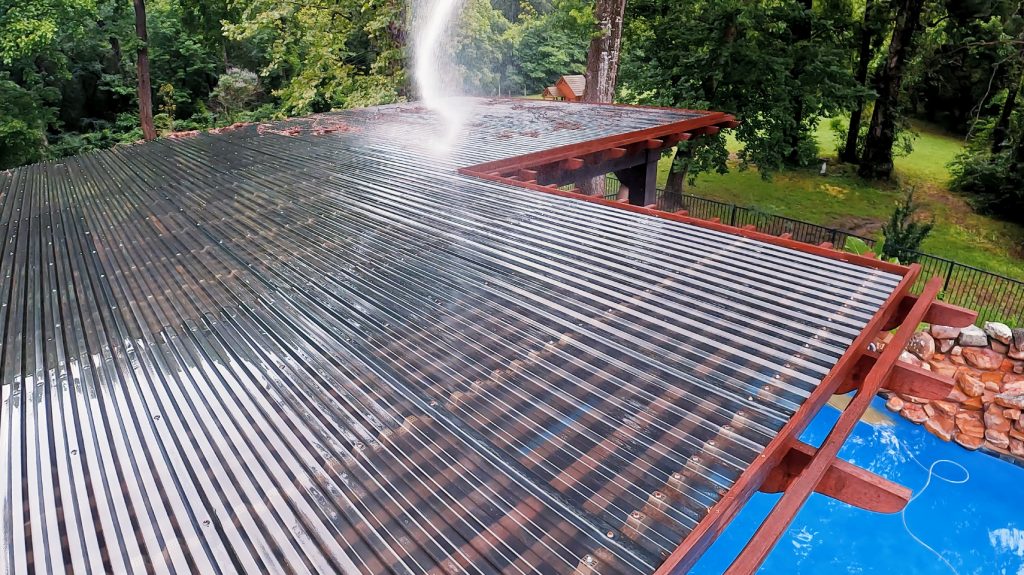 Water spraying debris off of a pergola overlooking a pool.