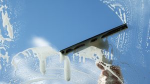 Squeegee wiping soaps suds off of a window